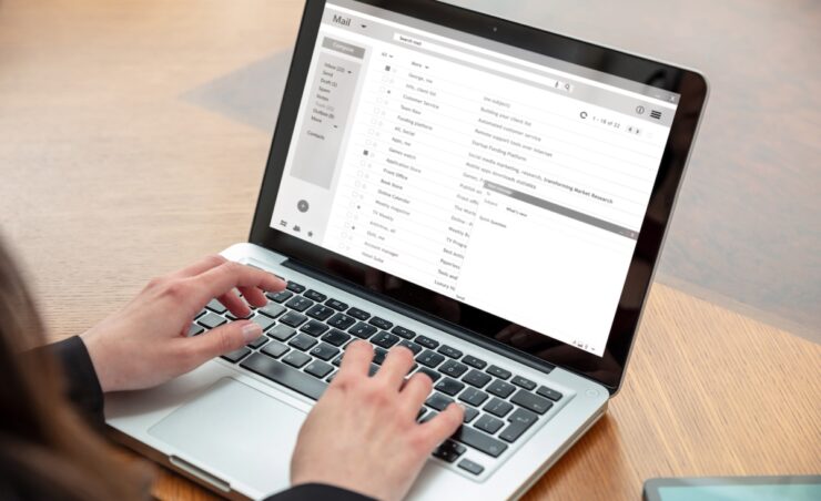 Email client list, woman working with a computer laptop, inbox e mail messages on the screen, business office desk background